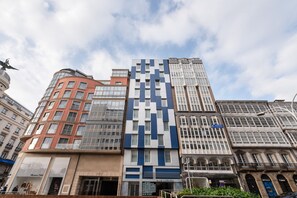 A row of modern buildings with varying architectural styles, including a prominent blue and white patterned building. - Eurostars Blue Coruña (A Coruña)