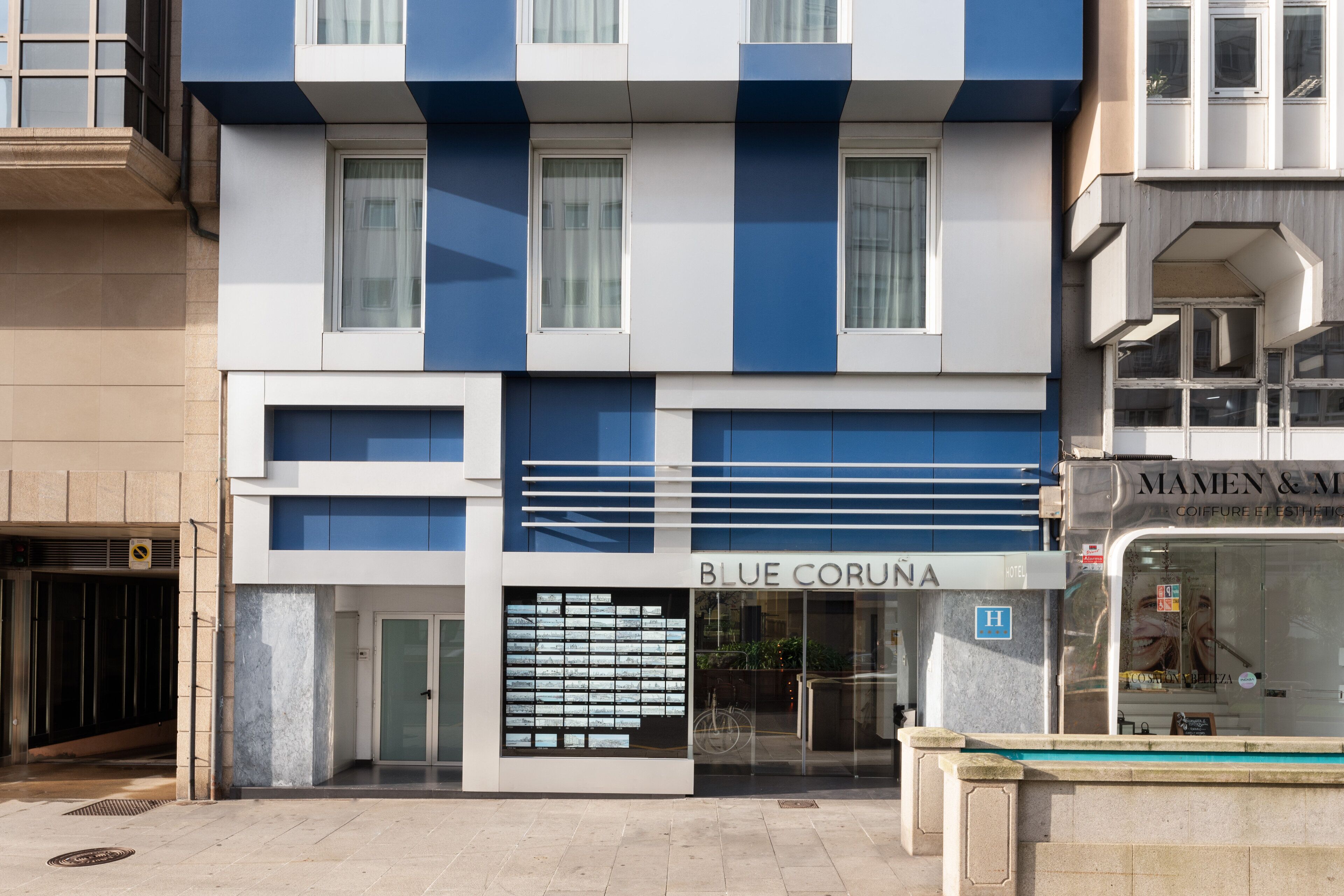 Un hotel llamado Blue Corona con una fachada moderna, amplias ventanas y una entrada visible.