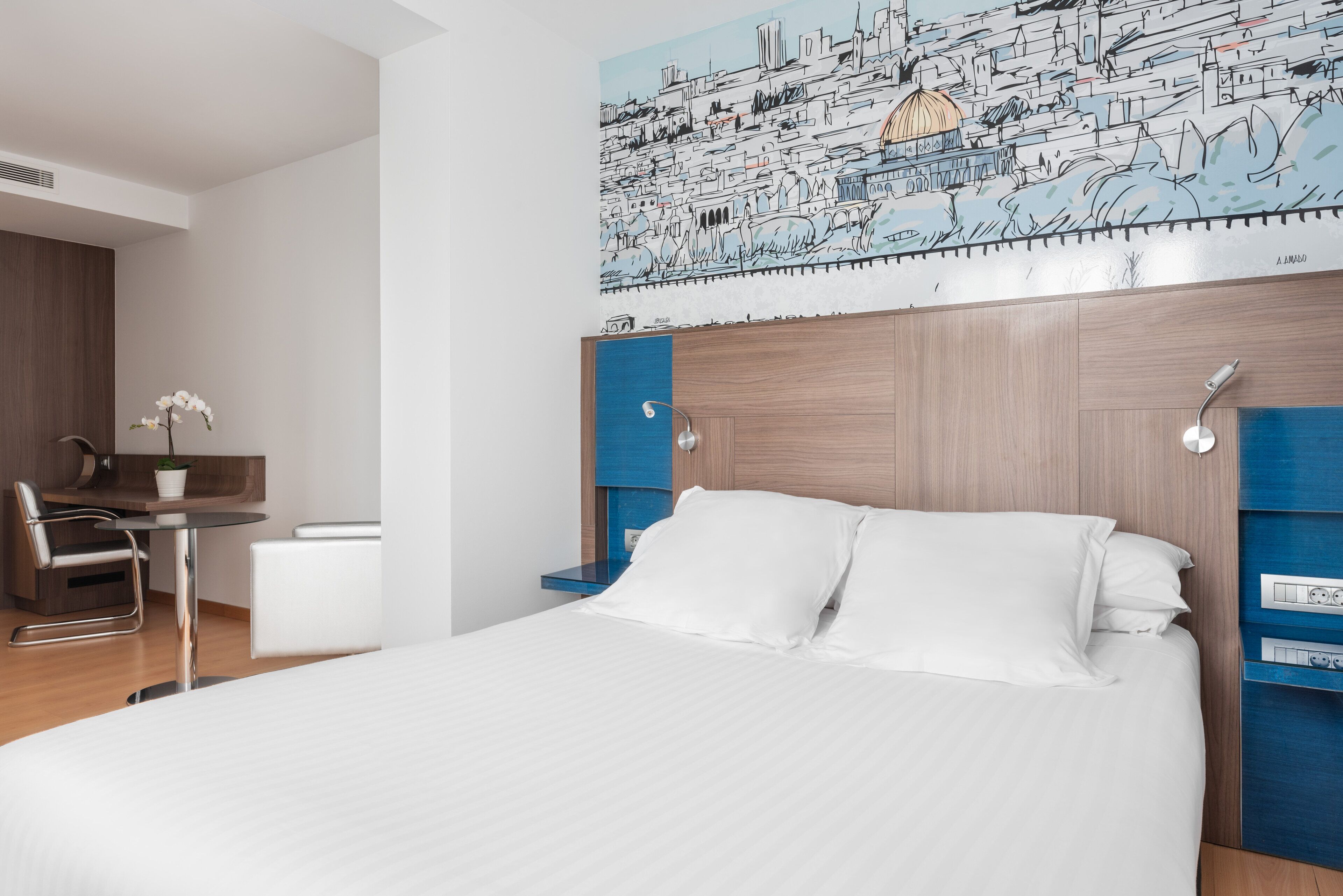 Una habitación de hotel moderna con una cama grande, un escritorio y una silla.