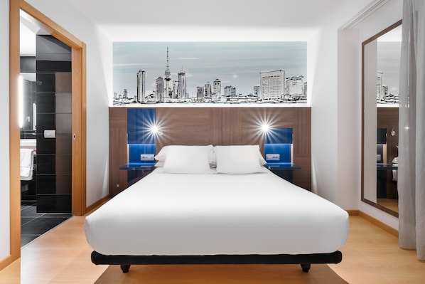 Quarto de hotel moderno com uma cama grande, um mural da paisagem urbana na parede, um guarda-roupa e uma mesa de cabeceira com uma luminária.