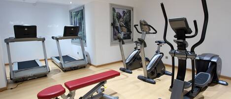 A gym with treadmills, elliptical machines, and a bench.