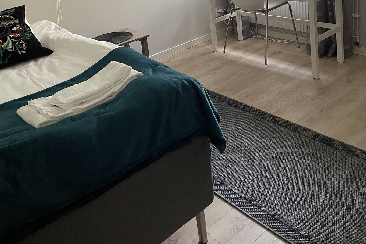 Une chambre à coucher avec un lit, un bureau et une fenêtre avec des rideaux.