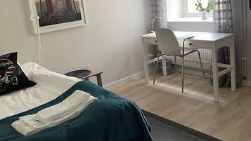 A bedroom with a bed, a desk, and a window with curtains.