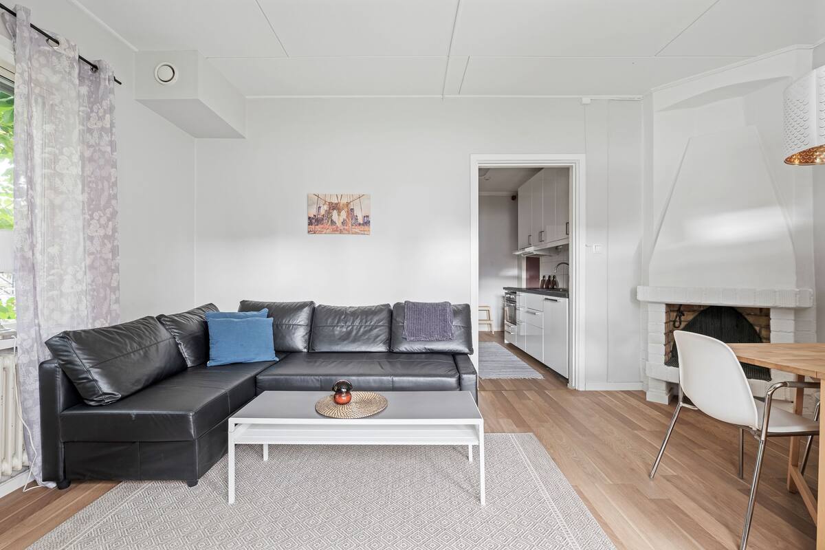 Un salon moderne avec un canapé en cuir noir, une table basse blanche et un coin repas avec une chaise blanche.