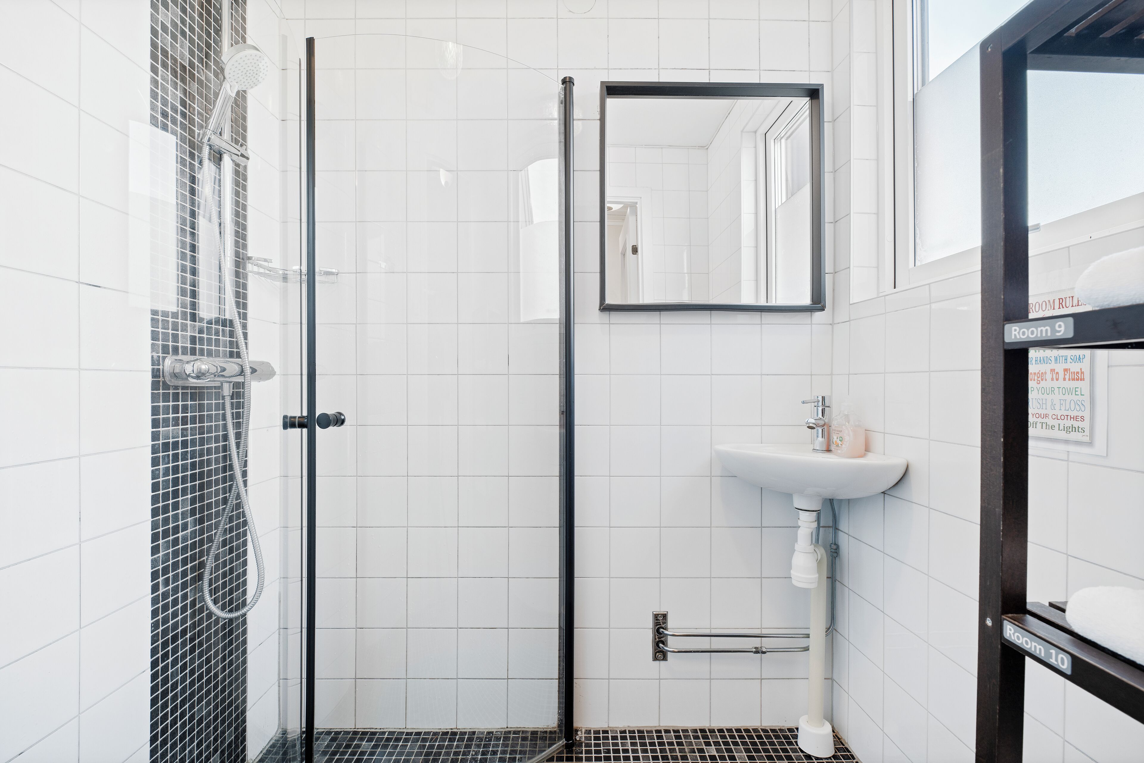 A modern bathroom with a glass shower enclosure, a white sink, and a mirror.