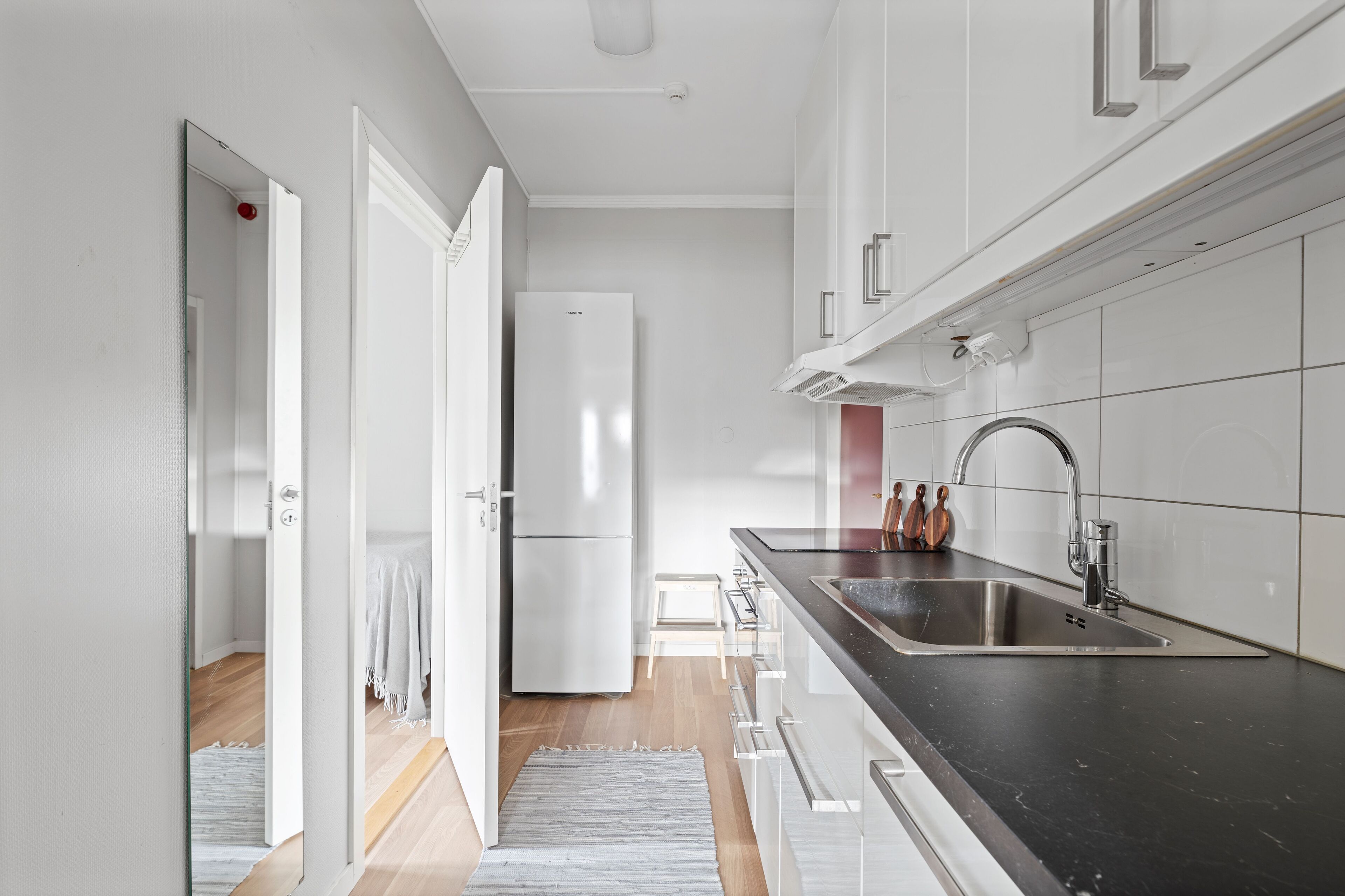 A modern kitchen with white cabinets, a stainless steel sink, and a built-in refrigerator.
