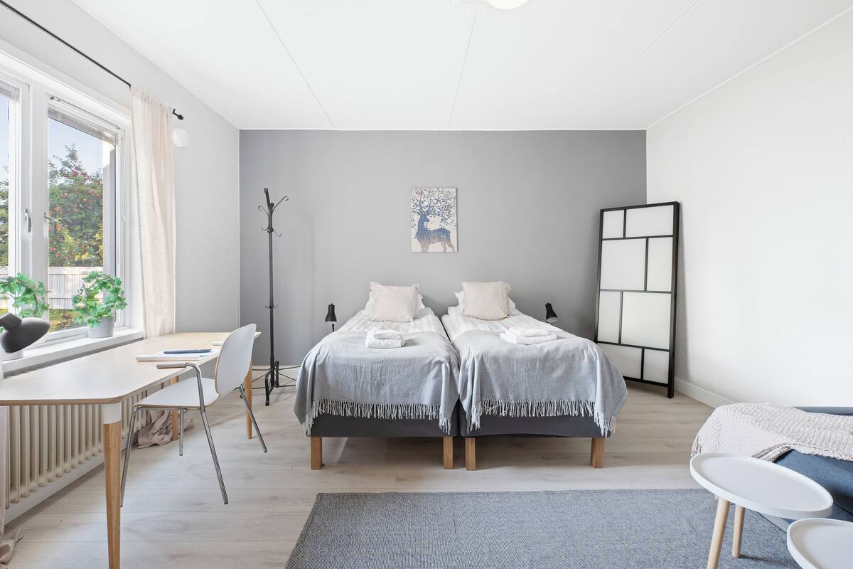 Une chambre moderne avec deux lits, un bureau et une chaise.