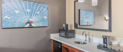 Une salle de bain moderne équipée d’un grand miroir, d’un lavabo, d’un four à micro-ondes et d’une machine à café.
