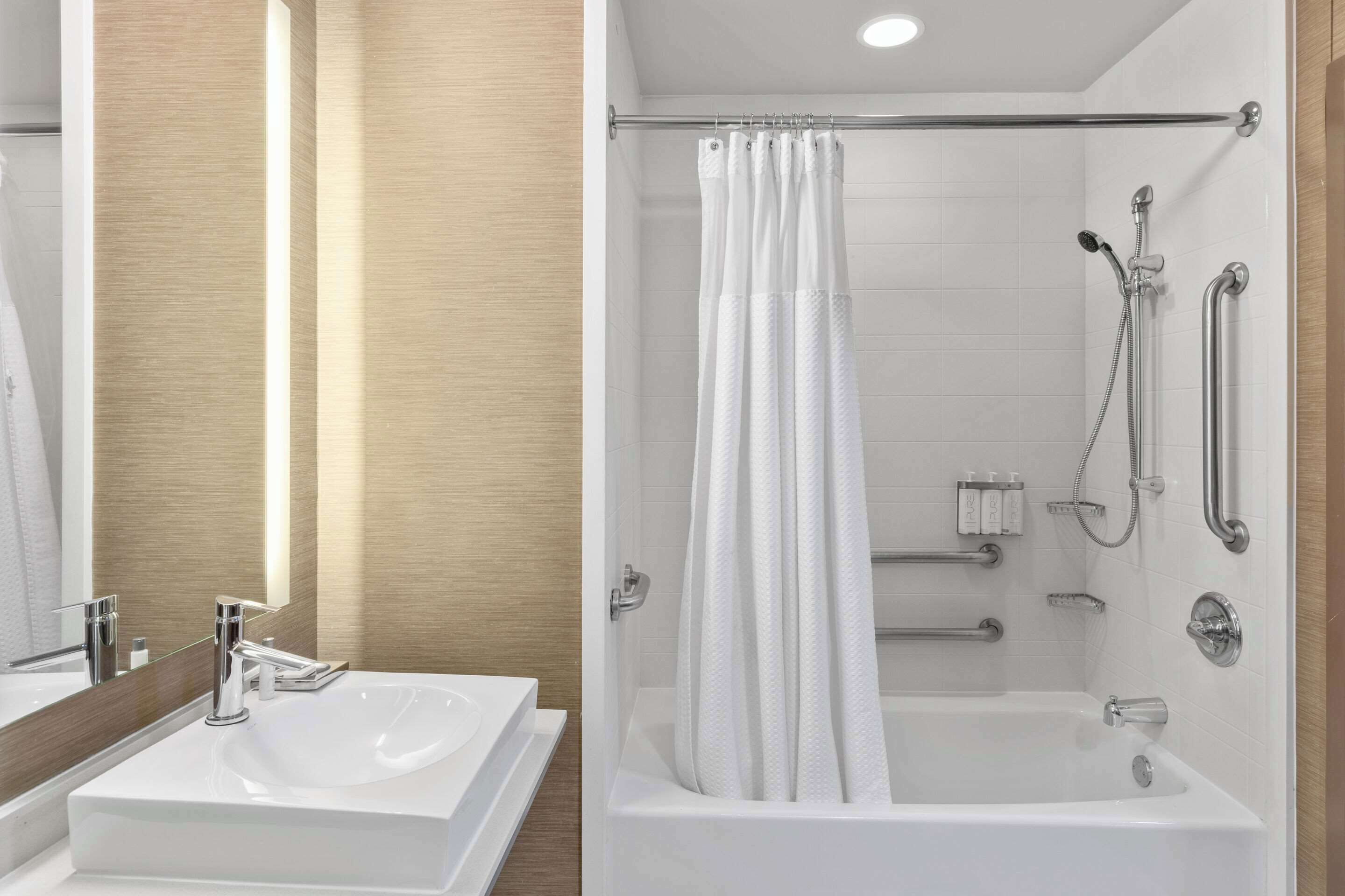 Un baño moderno con lavamanos blanco, espejo y zona de ducha.