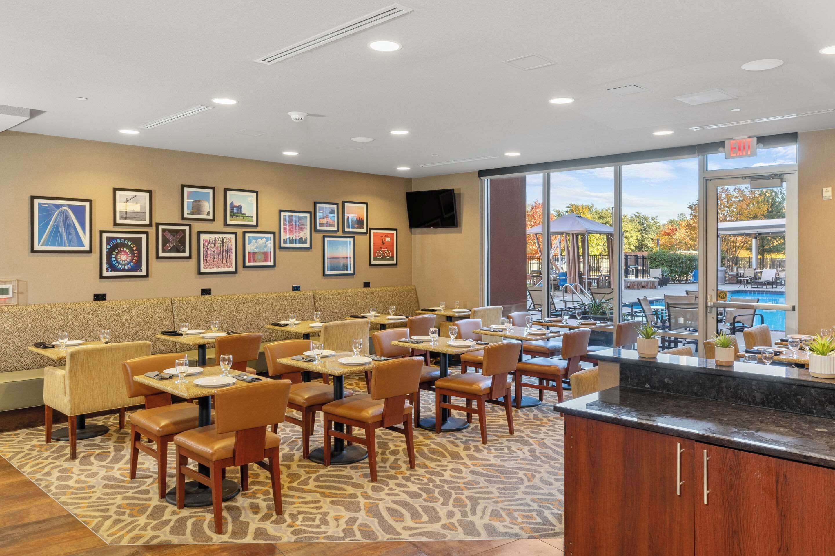 A restaurant with booths and tables, framed pictures on the wall, and a view of the outdoor pool area.
