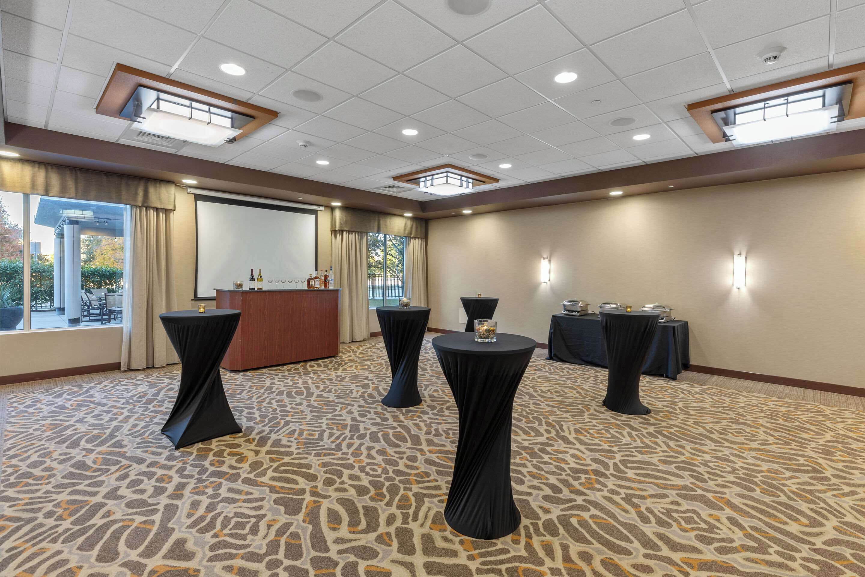 Un salón de conferencias con un escenario, mesas y una mesa de recepción.