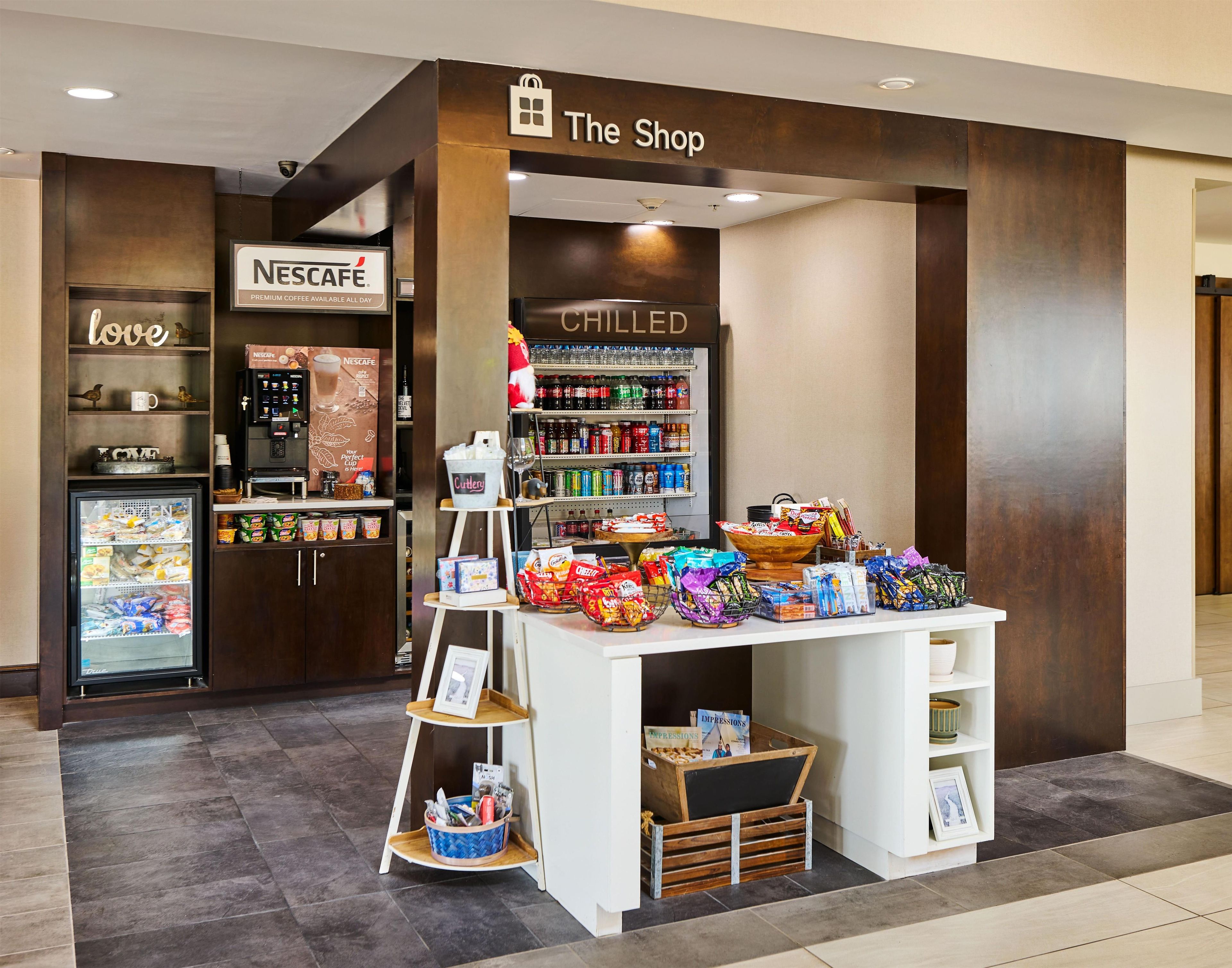 A shop with a Nescafé coffee machine, chilled beverages, and snacks.