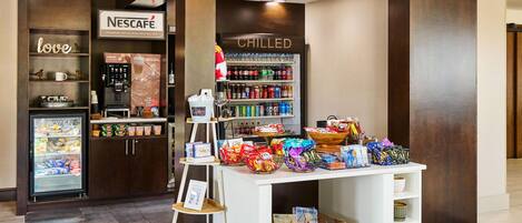A shop with a Nescafé coffee machine, chilled beverages, and snacks.