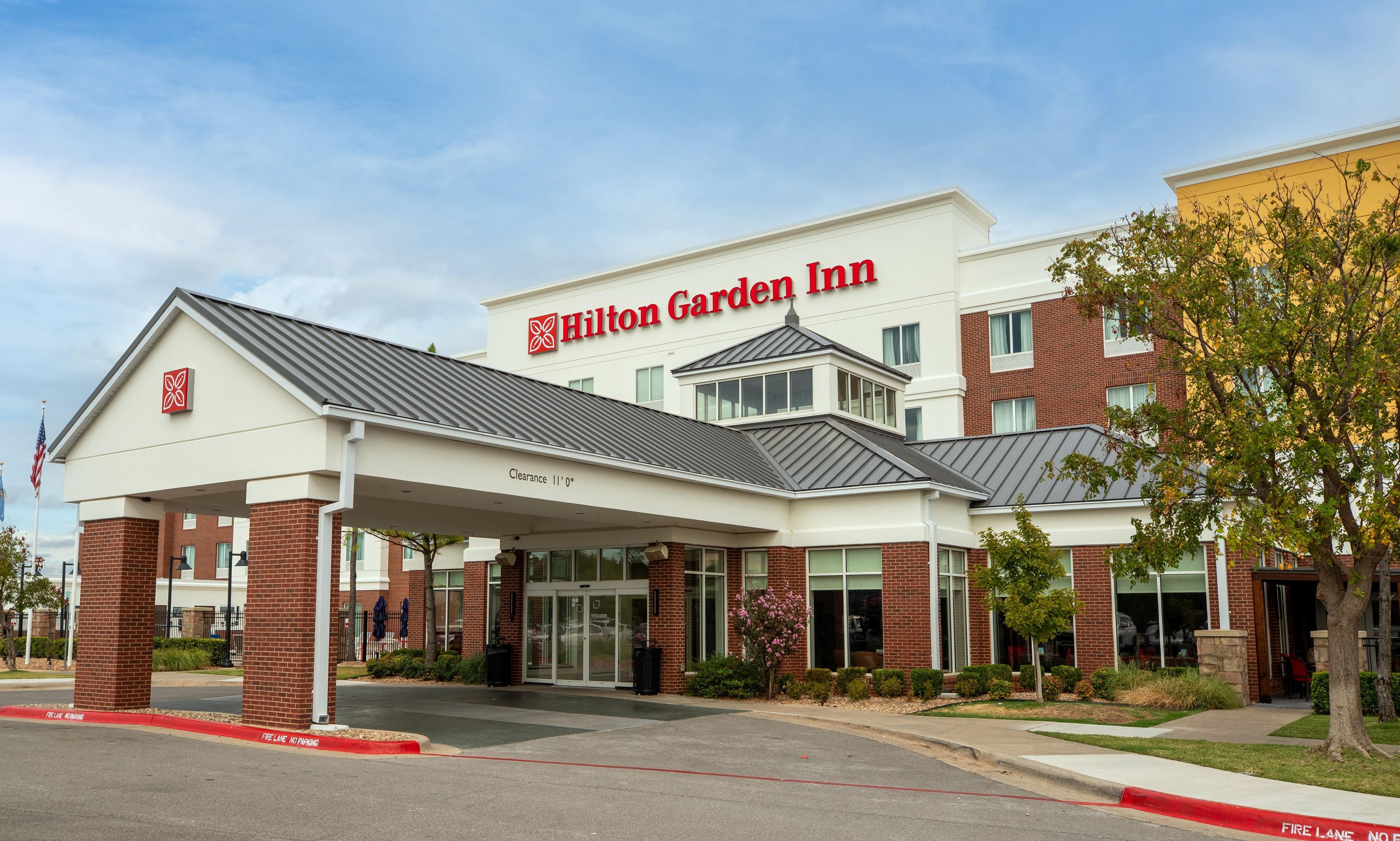 Un hôtel Hilton Garden Inn doté d’une entrée abritée, d’une façade en briques et offrant une vue sur un ciel dégagé.
