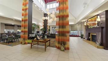 A spacious lobby with high ceilings, a central seating area, and a fireplace.