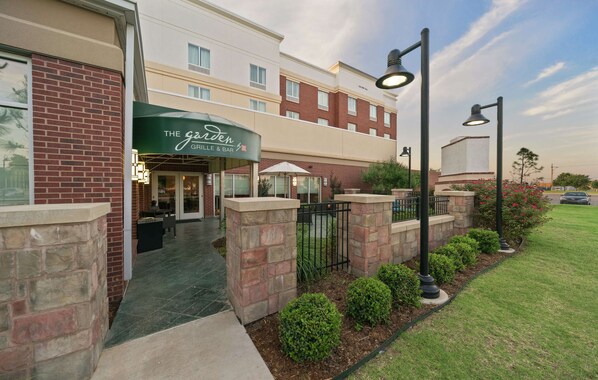 A hotel entrance with a green awning labeled "The Garden Grill & Bar." - Hilton Garden Inn Lawton-Fort Sill (Lawton)