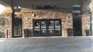 A building entrance with a stone facade, large double doors, and a covered walkway. - Hampton Inn Indianapolis NW/Zionsville (Whitestown)