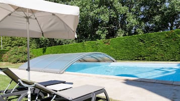 Una piscina al aire libre, sillones reclinables de piscina
