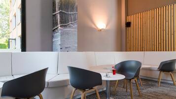 A modern interior with a white sofa, black chairs, a round table, and a wall-mounted light.