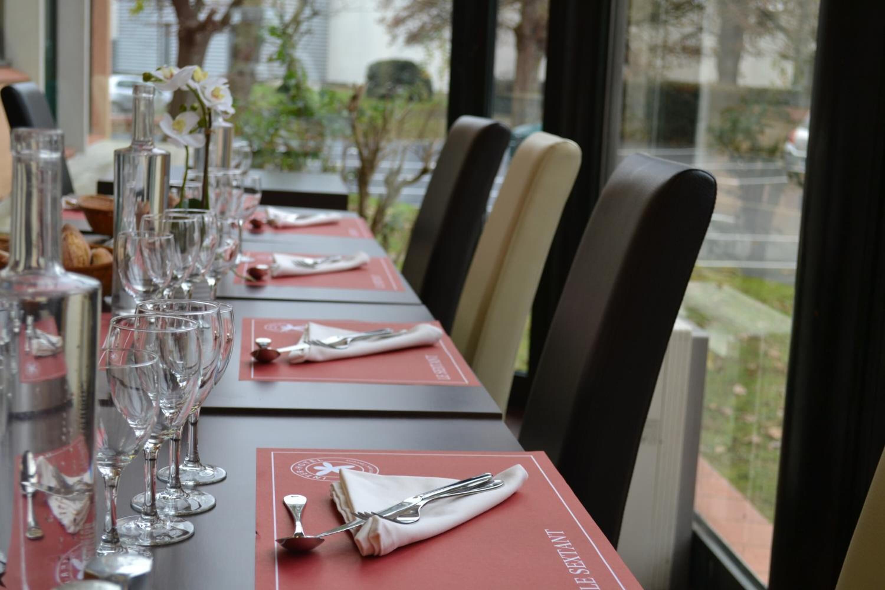 Una mesa de comedor con copas de vino, cubiertos y una carta.