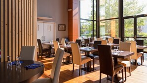 A restaurant with wooden paneling, large windows, and multiple tables and chairs. - The Originals City, Hôtel Le Sextant (Labege)
