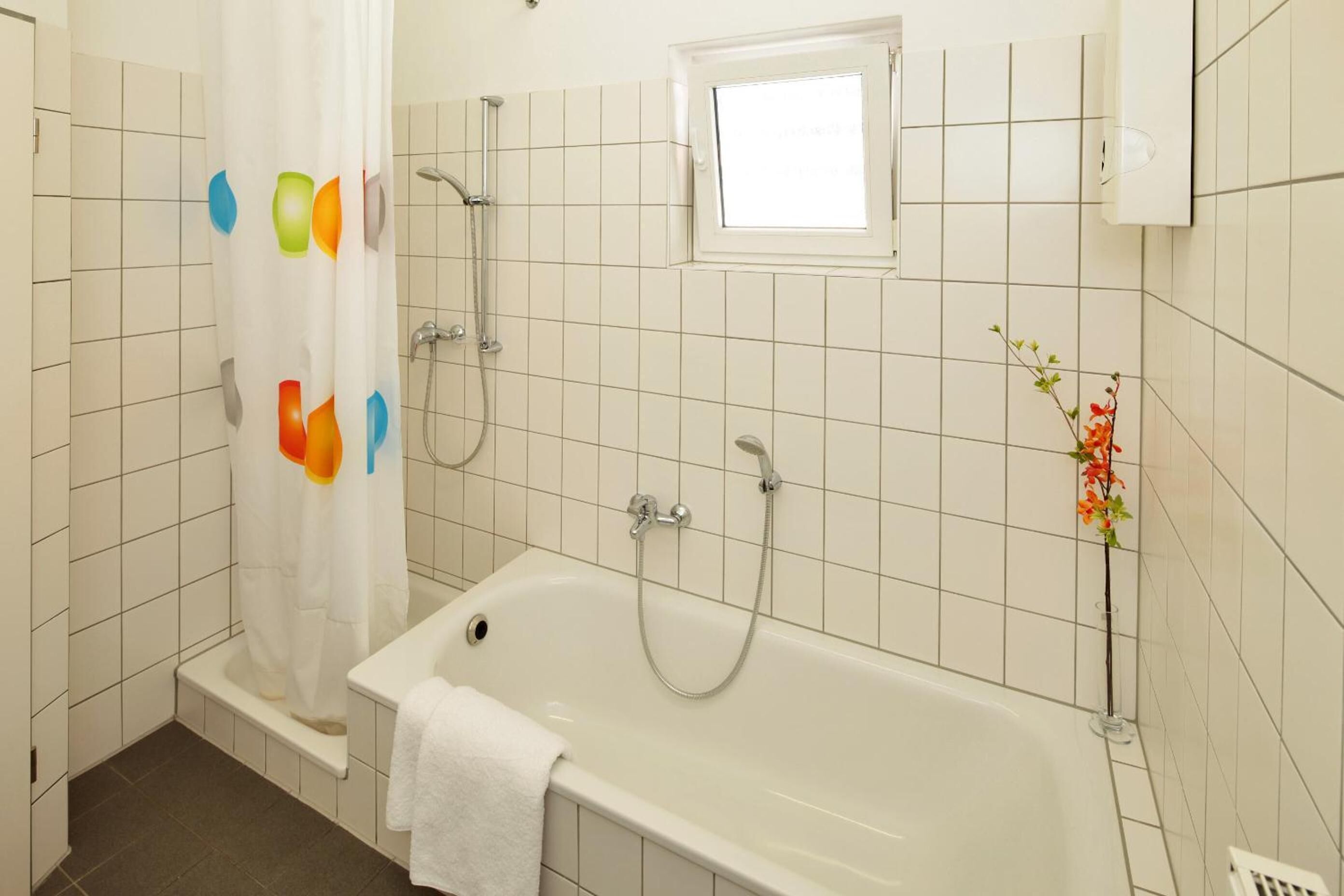 A bathroom with a bathtub, shower, and a window.