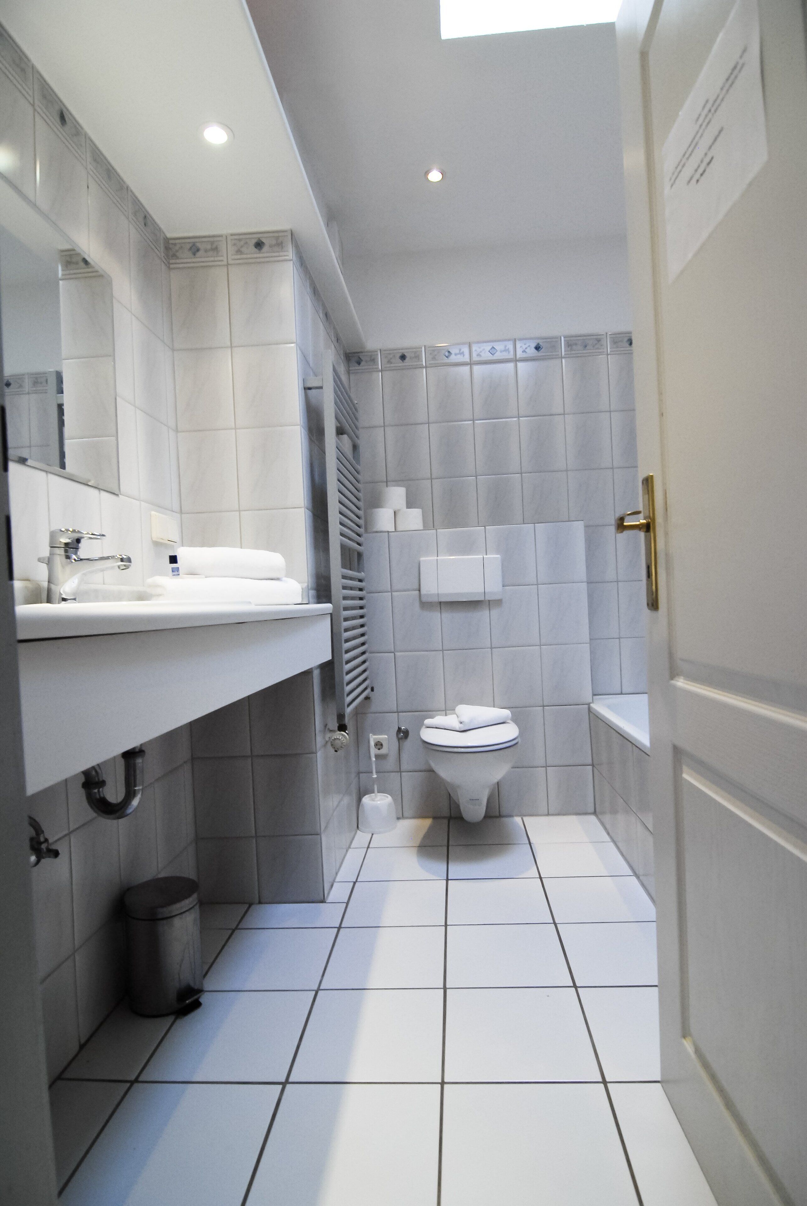 Ein modernes Badezimmer mit Waschbecken, Spiegel und Toilette in Weiß.