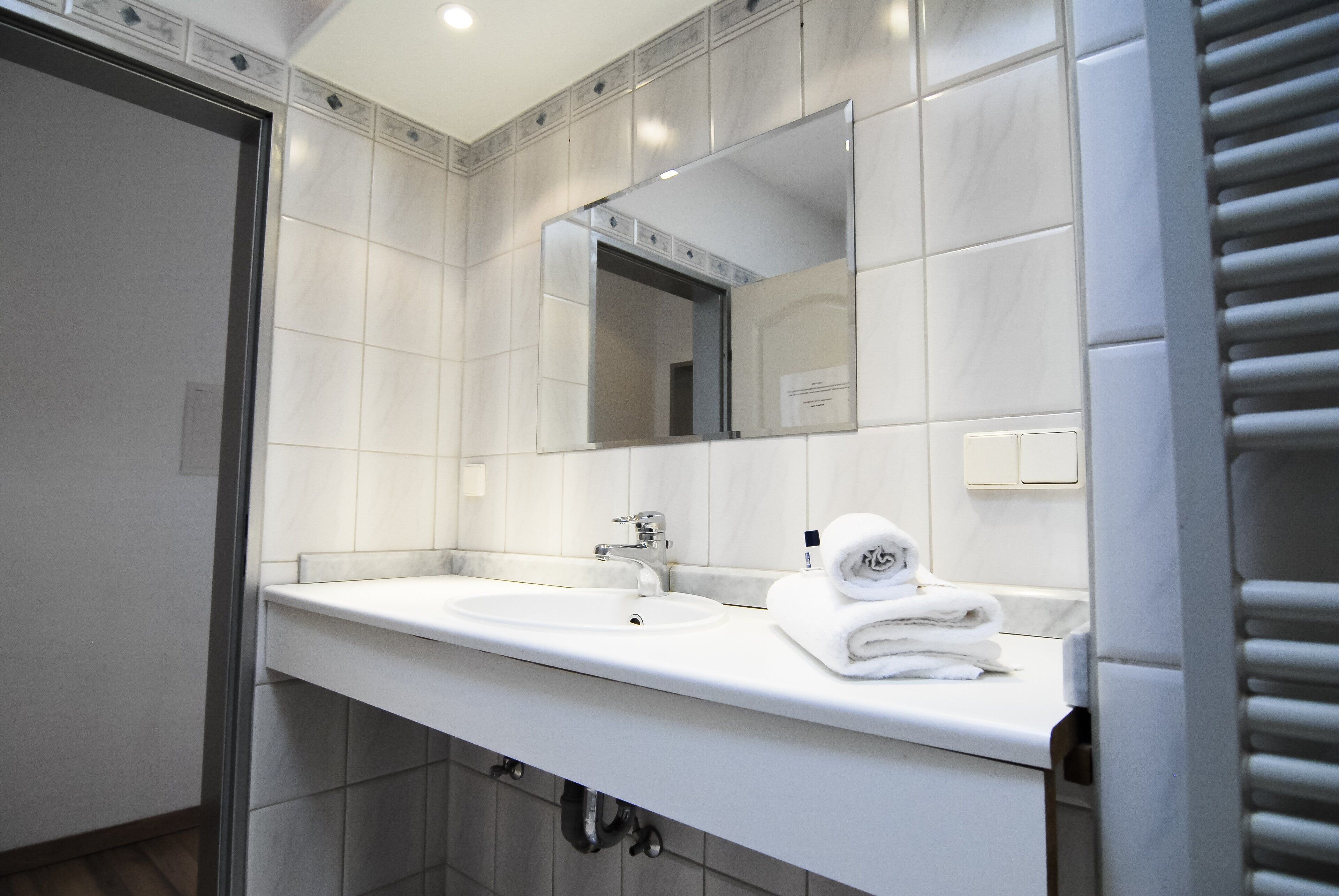 A modern bathroom with two sinks, a large mirror, and a towel rack.