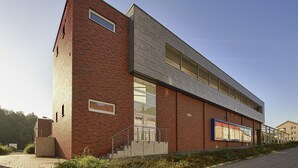 A modern building with a brick facade, large windows, and a visible entrance. - Petul Apart Hotel Residenz (Essen)