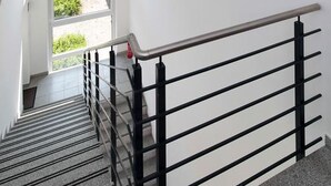 A staircase with black railings and a window at the top. - Petul Apart Hotel Residenz (Essen)