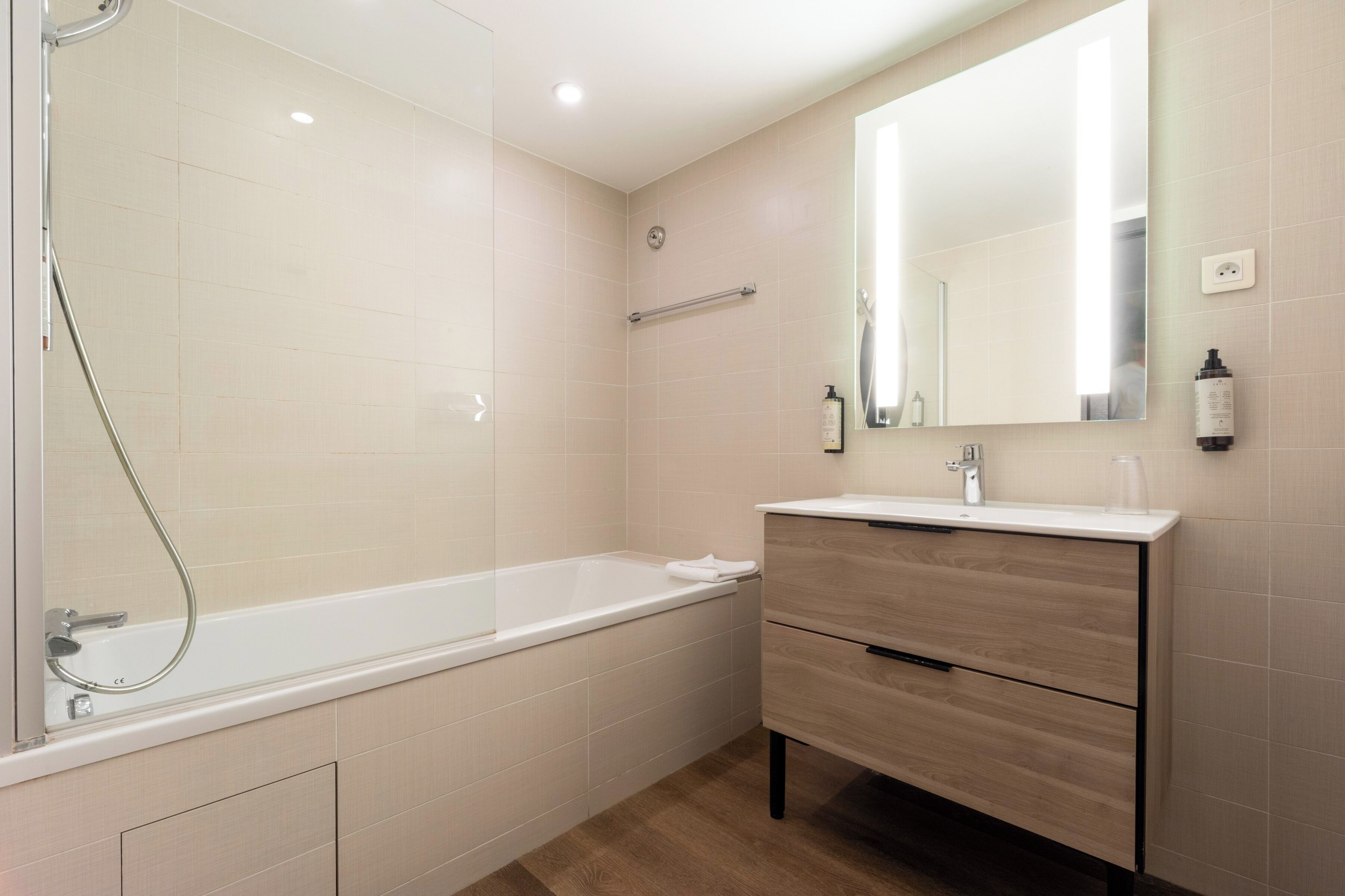 A modern bathroom with a bathtub, a vanity with a mirror, and a towel rack.