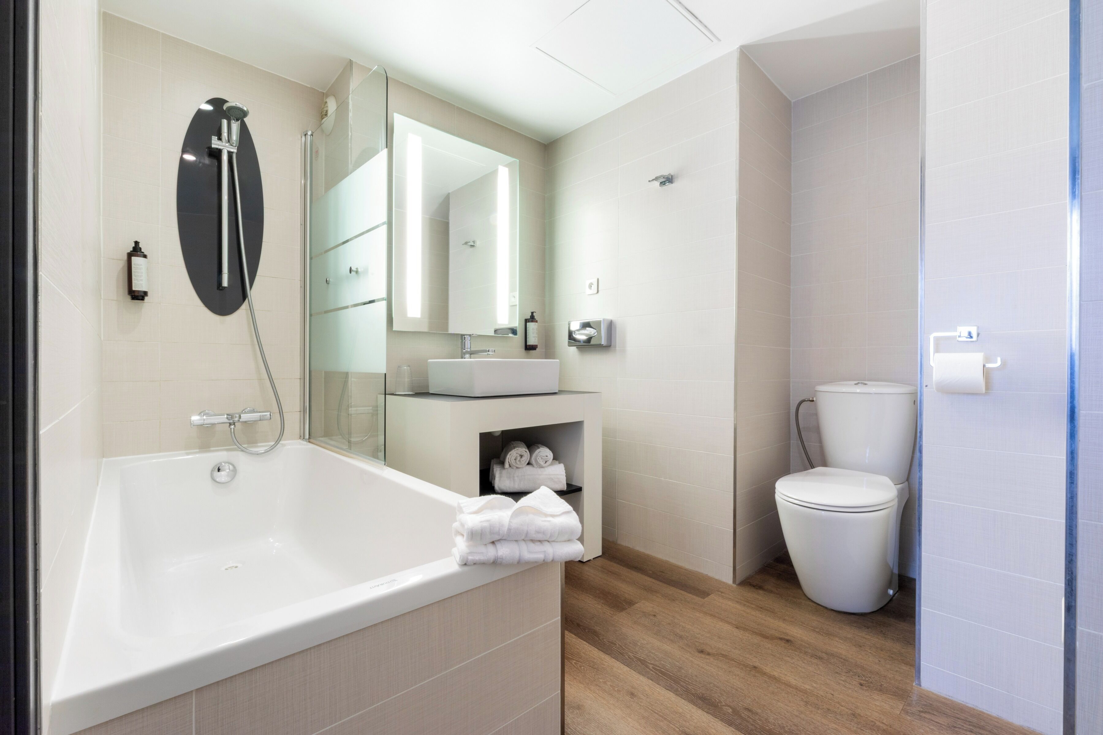 Un baño moderno con bañera, inodoro, lavamanos y espejo.