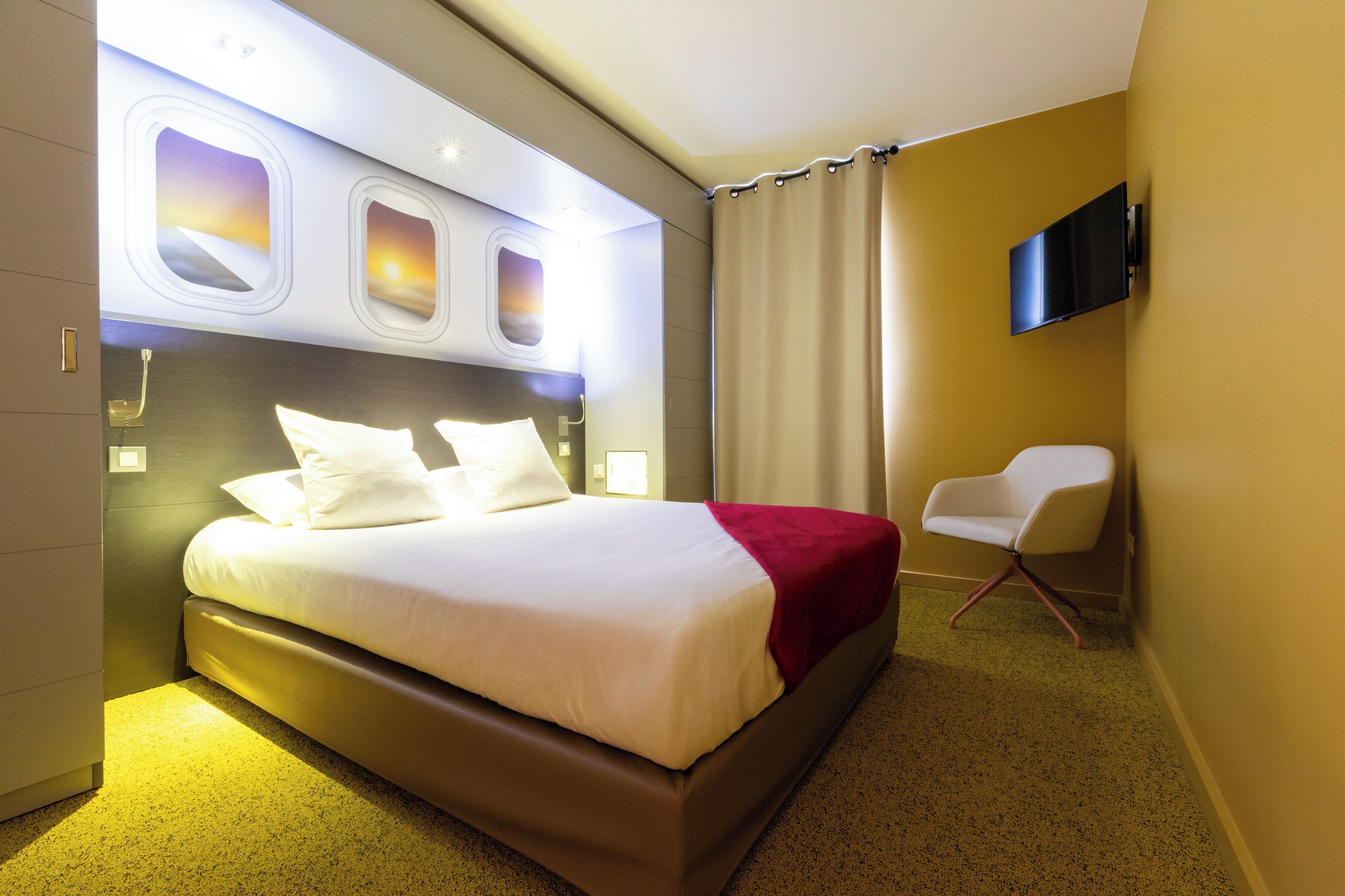 Une chambre d’hôtel avec un grand lit, un téléviseur fixé au mur et une chaise.