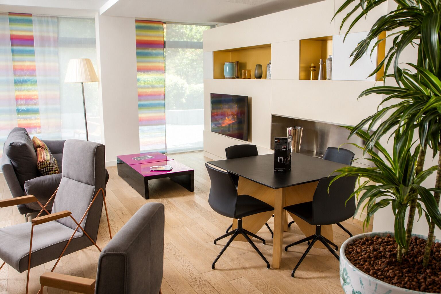 Un salon moderne comprenant une table à manger, des chaises, un canapé et une plante en pot.