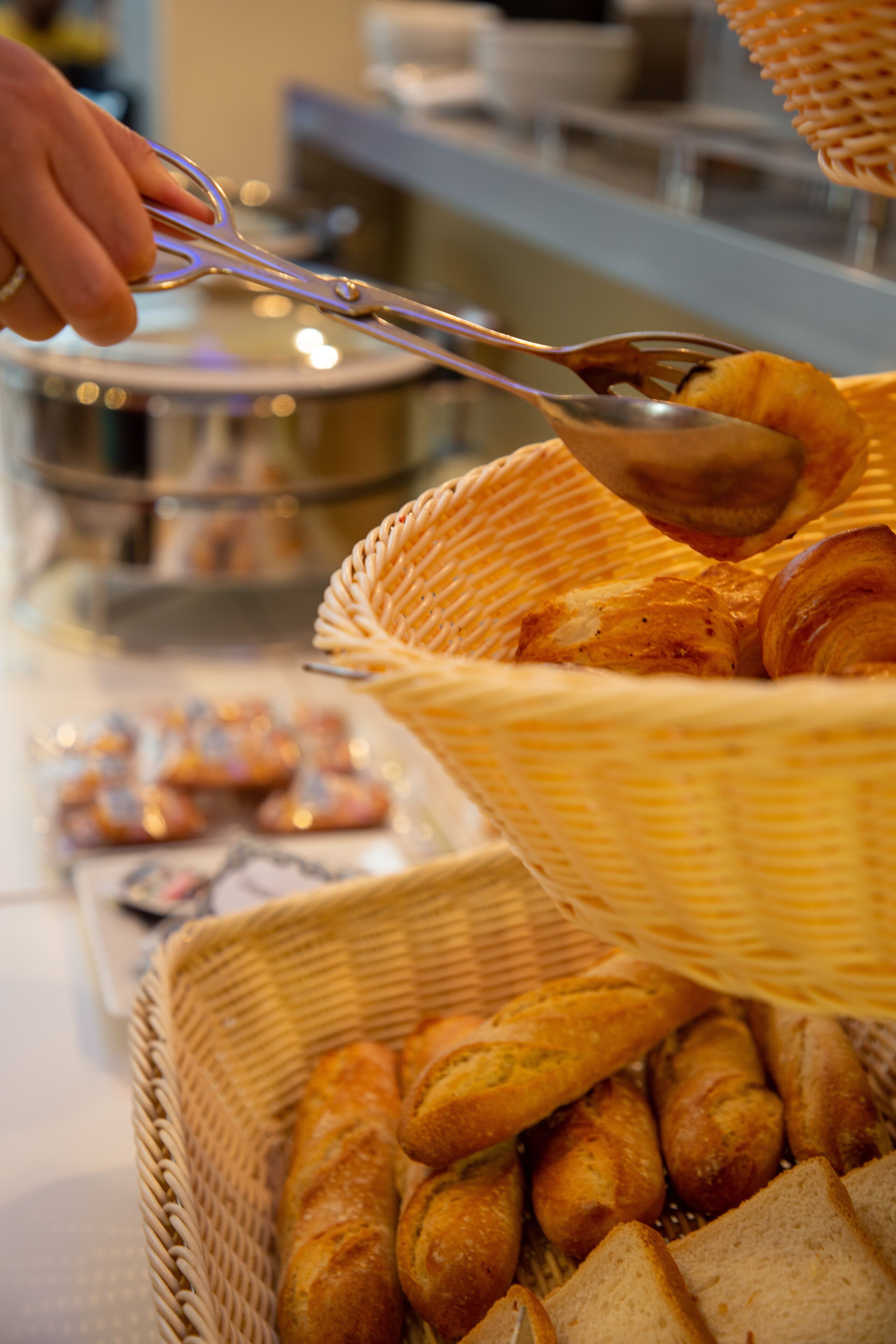 A basket filled with various baked goods, including bread and pastries, being served with a spoon.