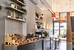 Una cocina moderna con estantes de madera, una cafetera y una zona de estar con sofá y sillones.