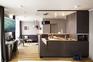 Una cocina moderna con una isla central, piso de madera y un comedor con sofá y mesa.