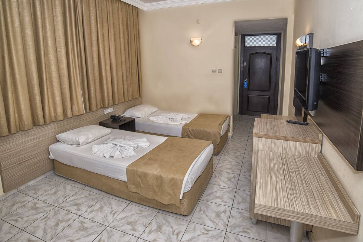 A hotel room with two beds, a TV, a desk, and a door with a checkered pattern.