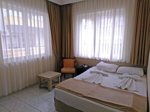 Una habitación de hotel con una cama, una silla, una mesita de noche y una pequeña mesa.