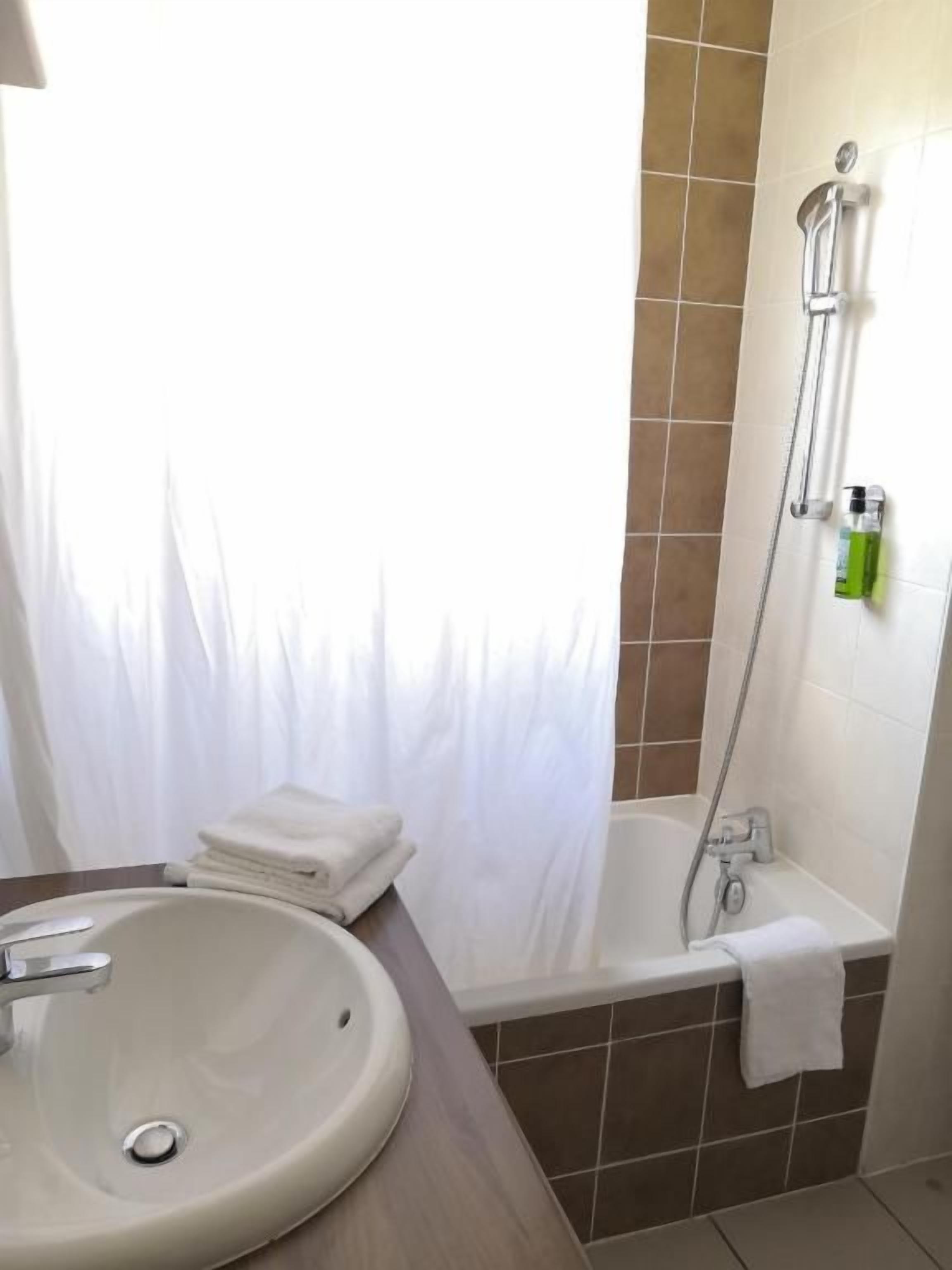 A bathroom with a sink, a shower, and a towel rack.