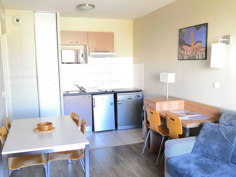 A compact living space with a dining area, kitchenette, and a sofa.