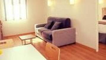 A modern living room with a sofa, a small table, and a window with curtains.