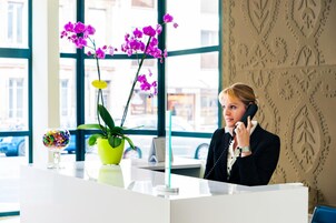 Una mesa de recepción con una planta en maceta y un recipiente de vidrio con objetos de colores.