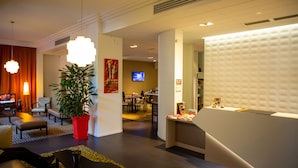 A hotel lobby with a reception desk, seating area, and a television. - Privilège Appart Hotel Saint-Exupéry (Toulouse)