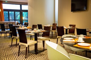 Un comedor de hotel con varias mesas y sillas, equipado con vajilla, tazas y cubiertos.