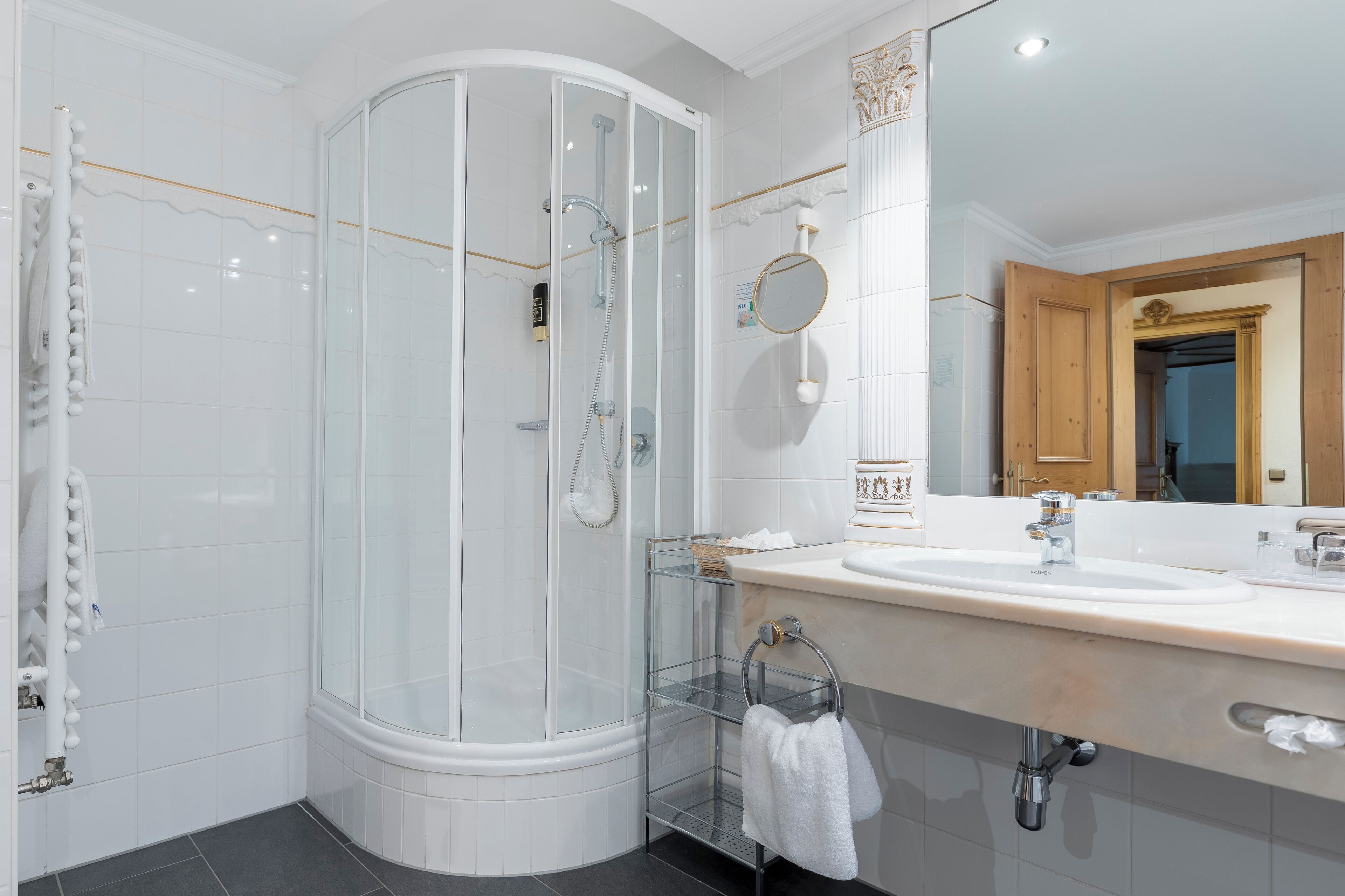 Un bagno moderno con cabina doccia in vetro, un lavandino bianco e uno specchio con cornice in legno.