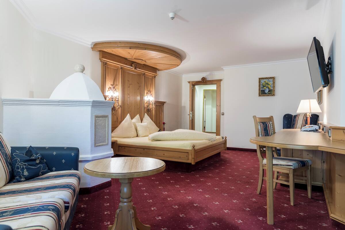 A room with a bed, a sofa, a dining table, and a television.