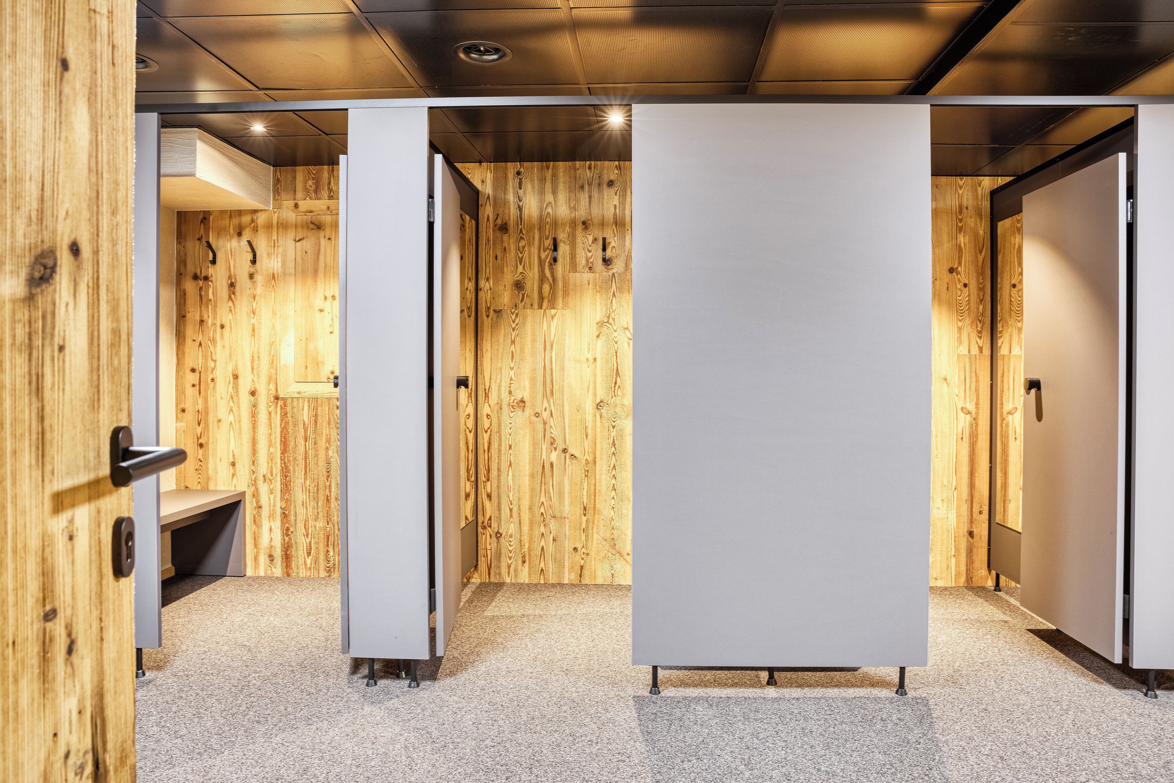 A modern interior with wooden panel walls, a bench, and a large white partition.