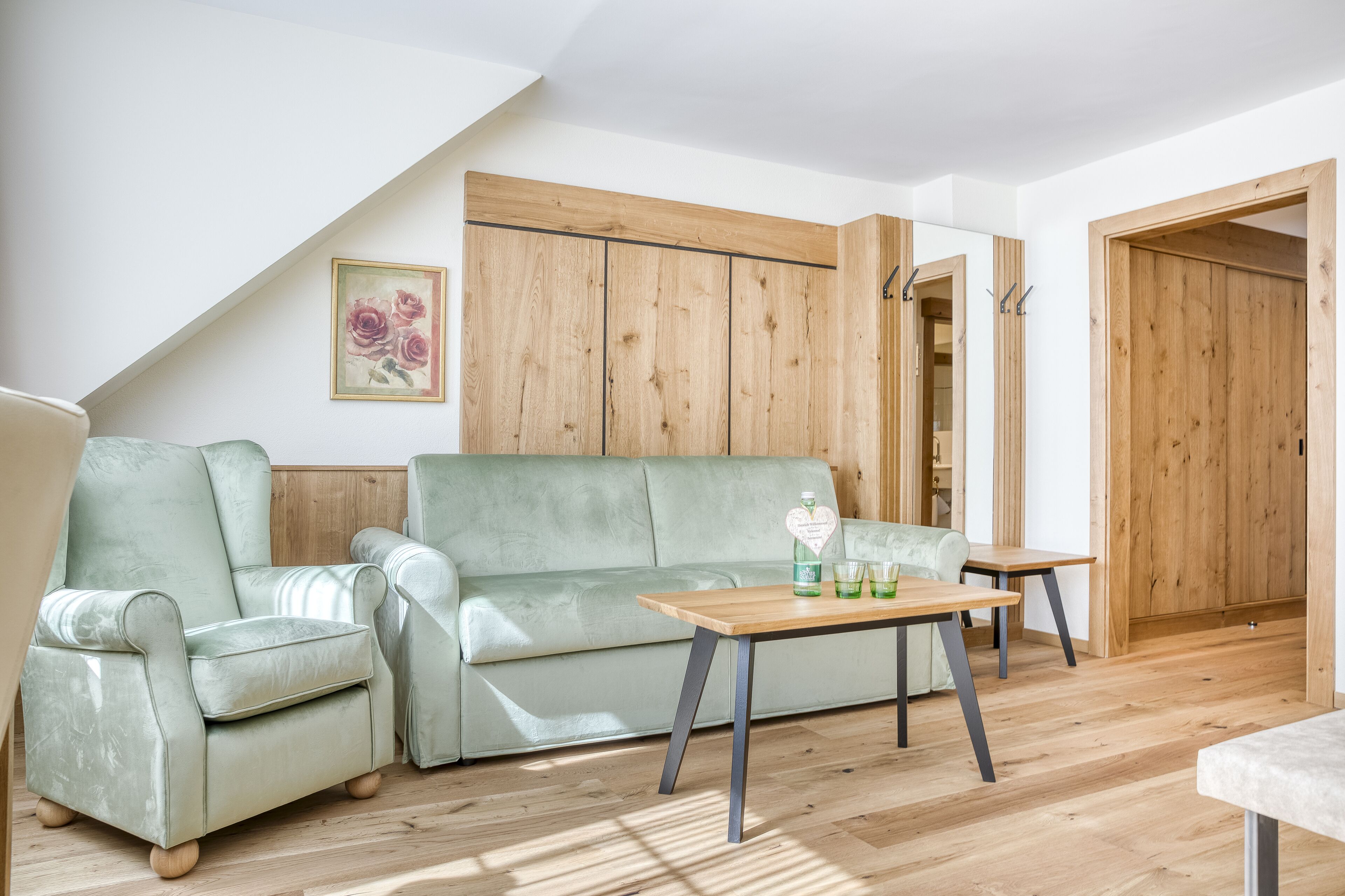 Un salon avec un canapé vert, une table basse en bois et une armoire en bois.