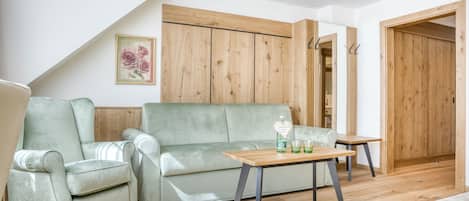 Un salon avec un canapé vert, une table basse en bois et une armoire en bois.